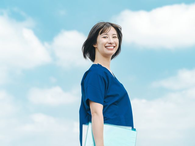 スタッフイメージ スタッフイメージ 青い服を着たスタッフが笑顔で立っています。優しさと安心感が感じられる雰囲気です。