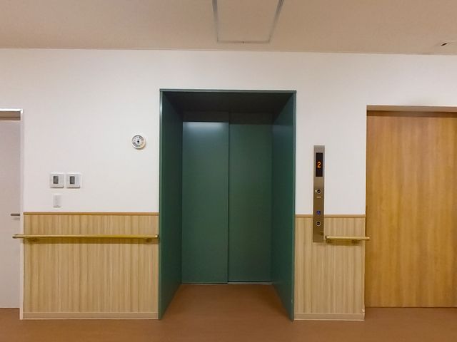 落ち着いた色合いのエレベーター エレベーター 手すりが付いた廊下に面したエレベーターです。快適な移動をサポートします。