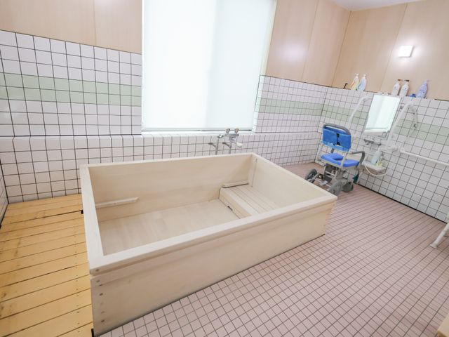 広々とした浴室 浴室 大きな浴槽と車椅子用シャワーチェアが完備された、快適な入浴空間です。自然光が差し込み、明るい雰囲気が特徴です。