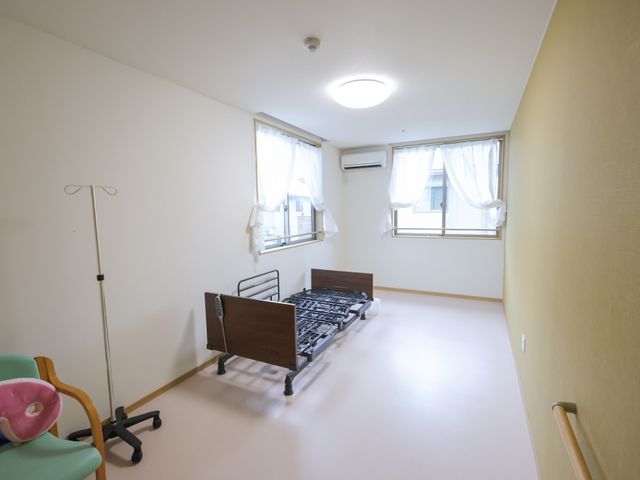 ベッドのある居室 居室 広々とした明るい部屋には、ベッドと椅子が備えられており、快適に過ごせます。自然光が優しく差し込みます。
