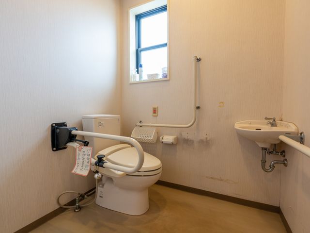 手すりが付いたトイレ トイレ 壁には手すりが設置されており、高齢者の方にも安全に利用いただけます。また、小窓から自然光が入り、明るい空間です。