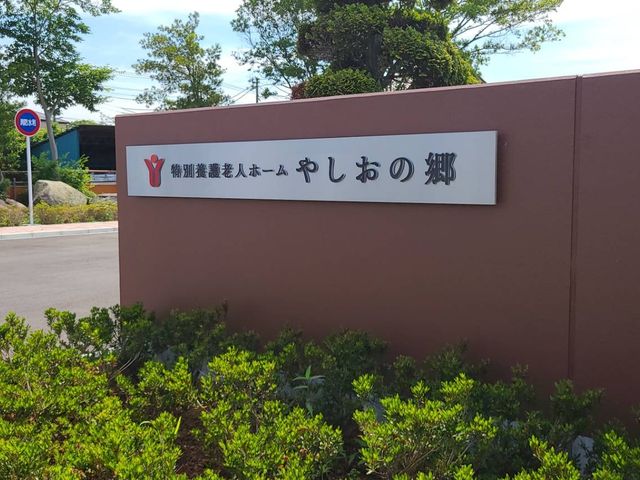 看板と敷地 看板 施設の入口には、訪問者を迎える印象的な看板があります。周辺には豊かな緑が広がっています。