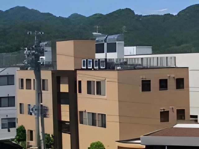 山を背景にした建物外観 外観 山に囲まれた静かな環境にあります。のどかな風景が広がる立地で働いてみませんか。