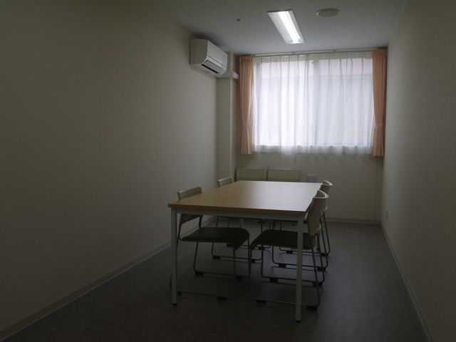 ゆったりした居室 会議室 広々とした部屋にはテーブルと椅子が備えられ、日差しが優しく差し込む居心地の良い空間です。