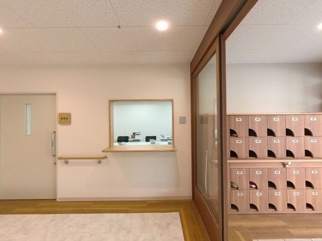 居心地の良い居室空間 フロント 木目調の温かみある床と、落ち着いた色合いの壁が特徴の居室です。利用者の方々が心地よく過ごせる環境が整っています。