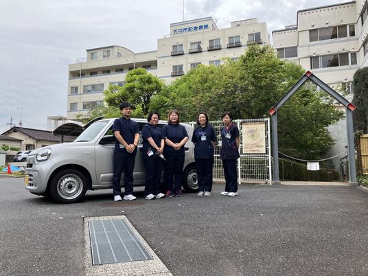 職員が並ぶ病院前  