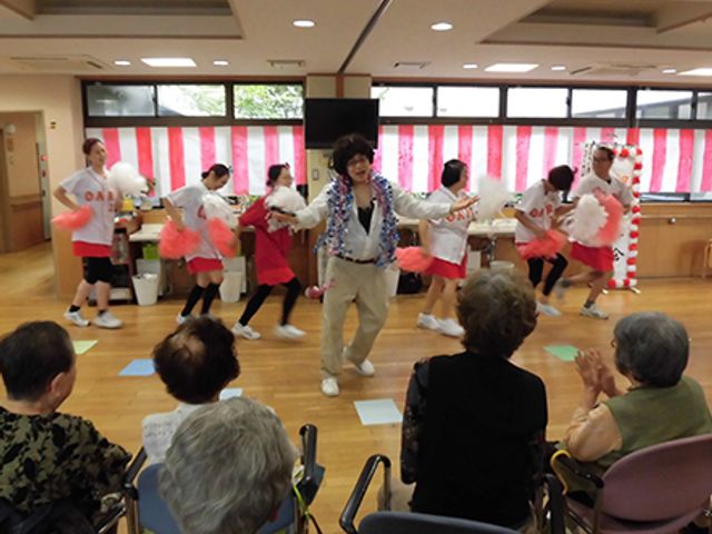 ダンスパフォーマンスの様子 多目的室 楽しいダンスパフォーマンスが行われており、居住者の方々が笑顔で楽しまれています。