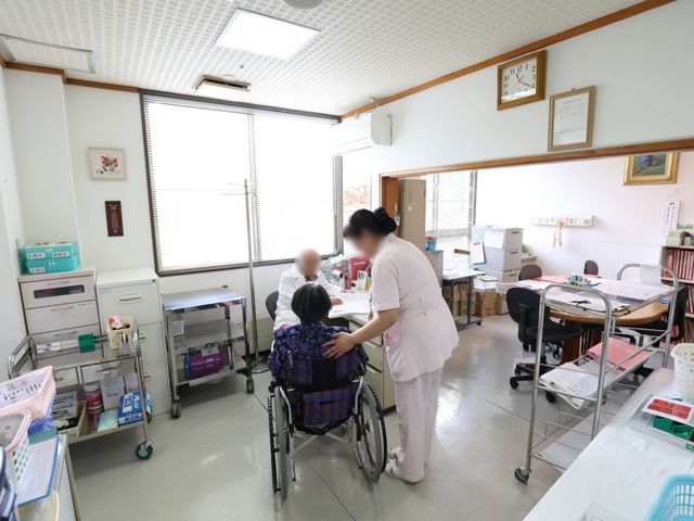 介護スタッフと利用者の会話 診察 心温まるスタッフのサポートが行われる場。利用者とのコミュニケーションを大切にしながら、日々の活動が支援されています。
