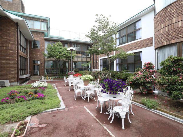 緑豊かな中庭 中庭 ゆったりとした時間が流れる中庭は、心安らぐ植栽と共に居心地の良い空間を提供しています。白いテーブルセットが置かれ、訪れた方々の憩いの場となっております。