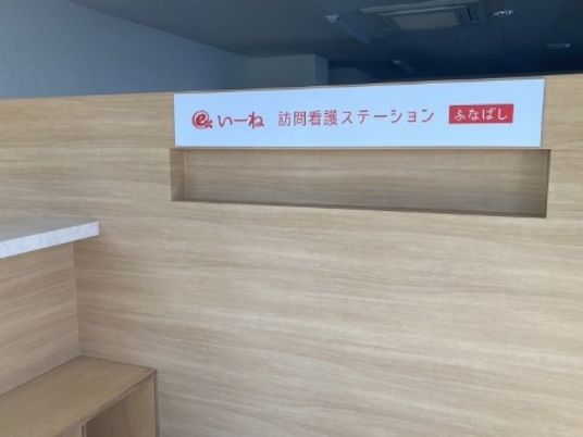 訪問看護ステーションの案内板と木目調壁のロビー  