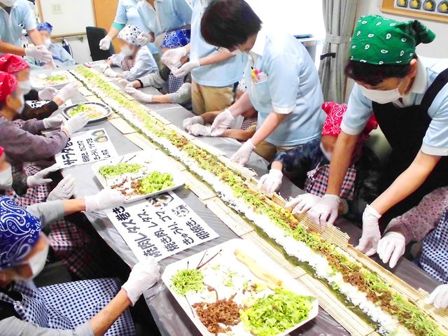 イベント活動の様子 多目的室 利用者が協力して巻き寿司を作っています。チームワークが求められる楽しい活動です。