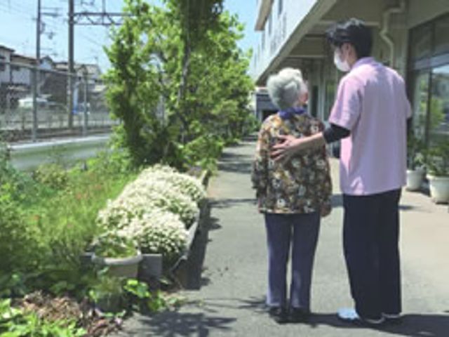 談笑する庭道 庭 敷地には落ち着いた庭があり、職員と利用者が穏やかに散策を楽しむことができます。