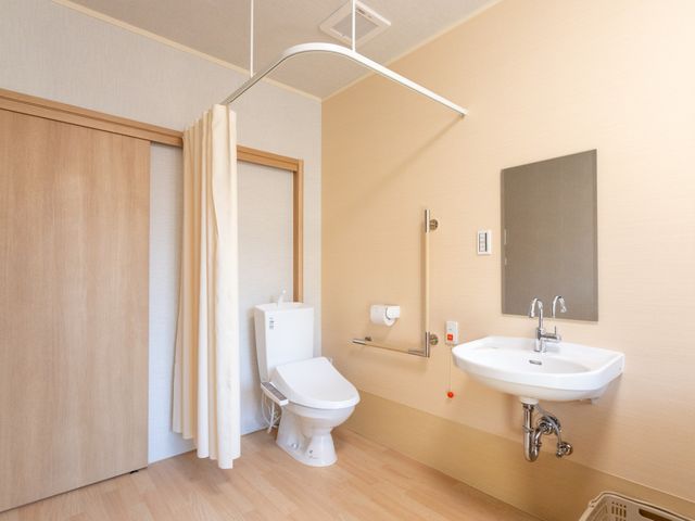快適なトイレ空間 トイレ 広々としたトイレは、手すりやカーテンが設置されており、安全で使いやすい設計です。