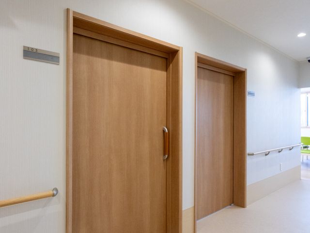 使いやすい廊下 廊下 木目調の扉が並ぶ廊下は、手すりがあり歩きやすくなっています。優しい照明で安心感を提供します。