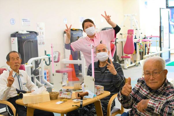 笑顔の利用者とスタッフの機能訓練室