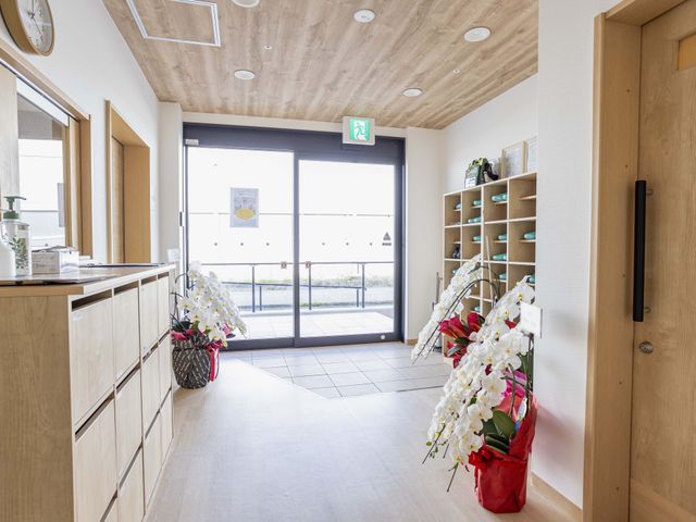 居室のエントランス エントランス 自然光がたっぷり入る明るい空間で、華やかな花々が並び、温かい雰囲気が漂っています。