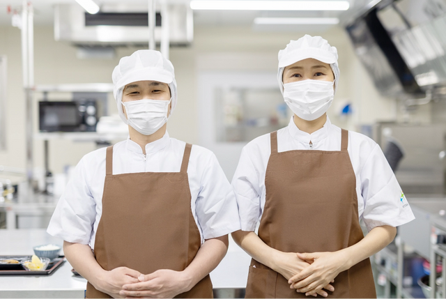 料理スタッフ二人のポートレート スタッフイメージ 清潔な厨房で笑顔のスタッフが、心を込めてお食事の準備をしてくれています。