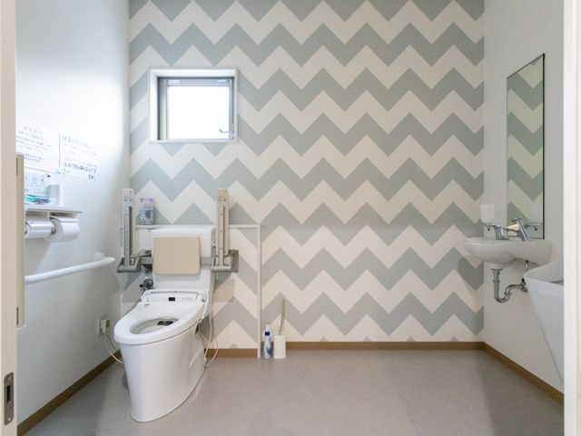 清潔な空間のトイレ トイレ サポートバー付きで安心できるトイレです。明るい壁紙が特徴的です。