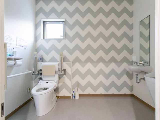 清潔な空間のトイレ トイレ サポートバー付きで安心できるトイレです。明るい壁紙が特徴的です。