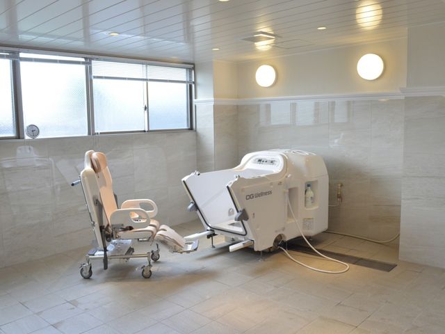 椅子付きバスタブの浴室 浴室 明るい空間で、安全に入浴できる設備があります。照明が柔らかく、清潔感にあふれています。