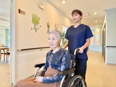 車椅子の女性とスタッフ廊下
