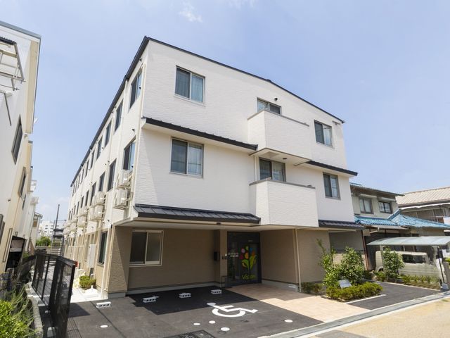 穏やかな外観 外観 柔らかな色合いの建物で、庭の緑が印象的な通路があります。快適な雰囲気を感じられます。