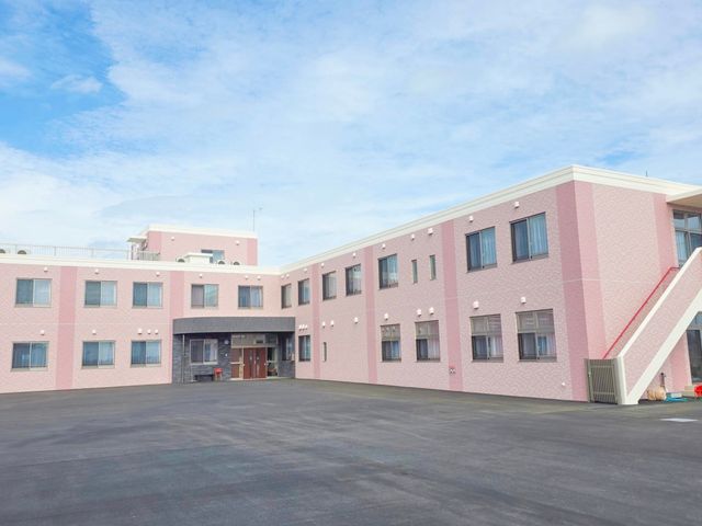 ピンクの建物外観 外観 ピンク色の広々とした建物で、優しい雰囲気があります。天気の良い日には快適に過ごせそうです。