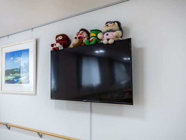 テレビがある廊下 廊下   壁掛けテレビの上にぬいぐるみが並び、手すりも付いた廊下です。移動しやすさに配慮した落ち着いた雰囲気が伝わります。