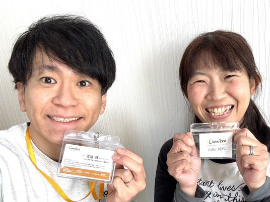 スタッフ2人が名札を掲げる様子  