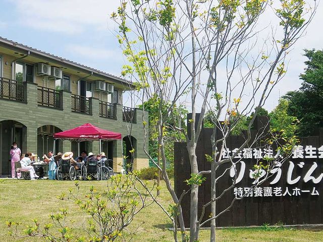 樹木と建物の庭 外観 庭では、多くの方がリラックスしながら過ごしています。緑に囲まれた開放的な風景です。