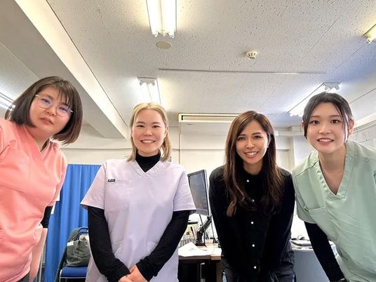 笑顔のスタッフが並ぶ室内  