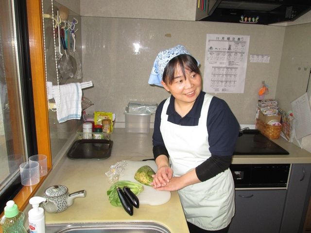 笑顔で調理するスタッフ キッチン 笑顔のスタッフが丁寧に調理をしており、清潔感あふれるキッチンであることが伺えます。