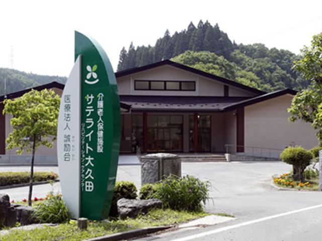 施設の看板と建物 外観 緑豊かな環境に囲まれた施設です。周囲の自然を感じながら働くことができます。