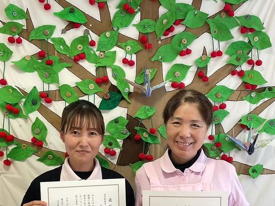 表彰状を持つ職員2人の前景  