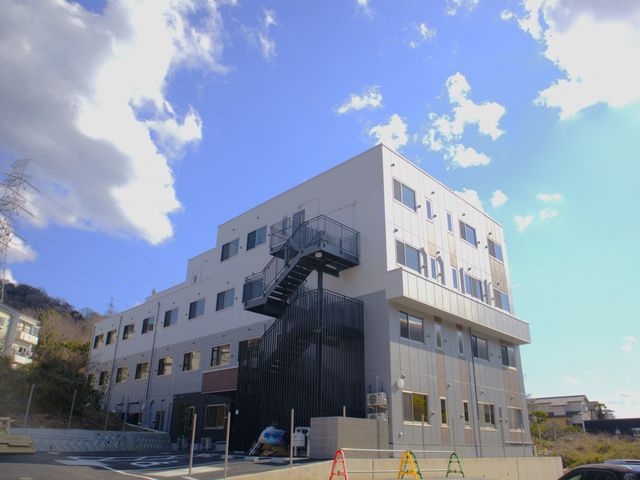 三階建ての建物 外観 青空を背景にそびえる三階建ての建物です。モダンなデザインが際立っています。