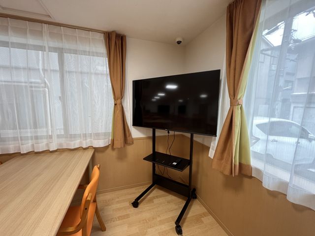 テレビとテーブルがある部屋 リビング 自然光が差し込むリビングルームには、テレビが設置されています。木製のテーブルと椅子で、温かみのある雰囲気です。