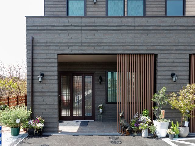 植物が飾られた建物外観 外観 モダンで落ち着いた印象の入り口です。豊かな植栽が並び、温かさを感じる場面です。
