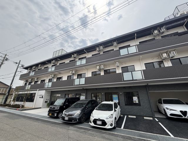 建物正面の駐車エリア 外観 車を停めやすい駐車エリアとモダンな建物が印象的な空間です。快適な職場環境を想像できます。
