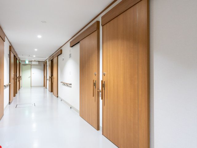 広い廊下 廊下 木製のスライドドアで仕切られた広々とした廊下です。手すりも設置されており、利用者に安全で快適な移動を提供します。