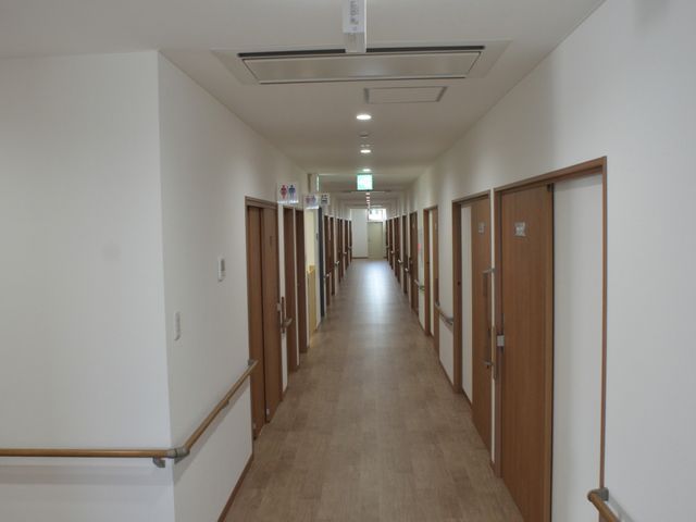 静かな廊下 廊下 優しい色合いの木製の床と手すり付きの廊下です。明るい照明が心地よい空間を演出します。