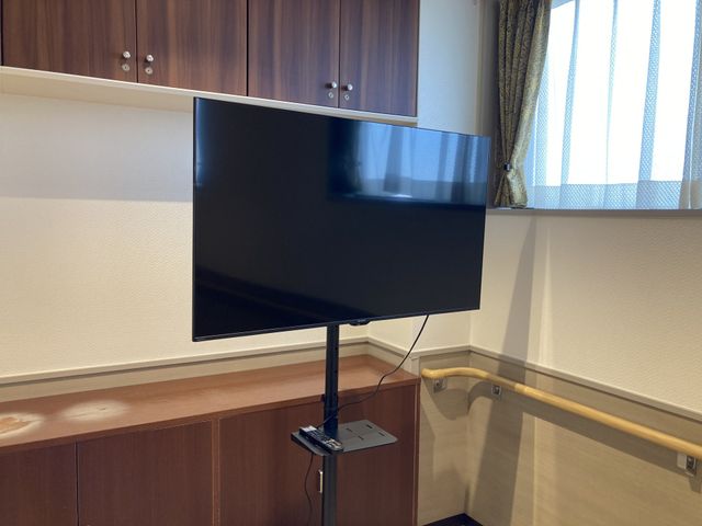 テレビのあるリビング リビング テレビ付きのスペースで、リラックスしながら利用者の方々が集まることができます。自然光が差し込む明るい空間です。