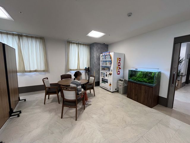 自販機と椅子の部屋 休憩室 開放的な休憩スペースで、明るい自然光が差し込みます。自販機があり、気軽に利用できる環境です。