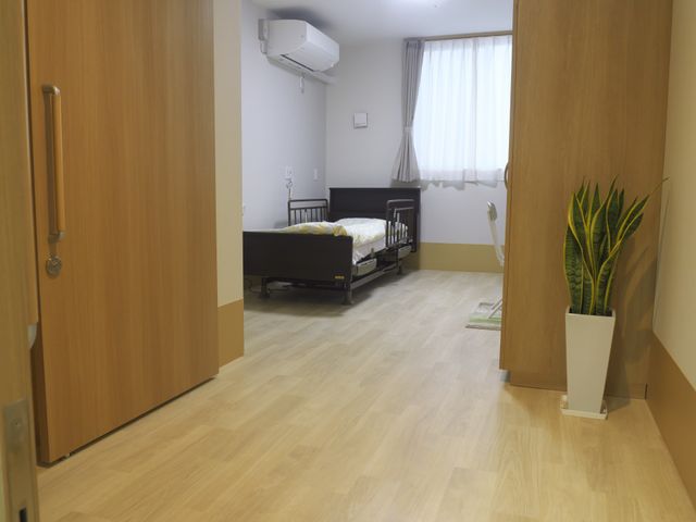 明るい個室 居室 自然光が差し込む個室は、温かみのある床材で落ち着いた雰囲気を演出しています。シンプルな家具配置で、快適に過ごせます。