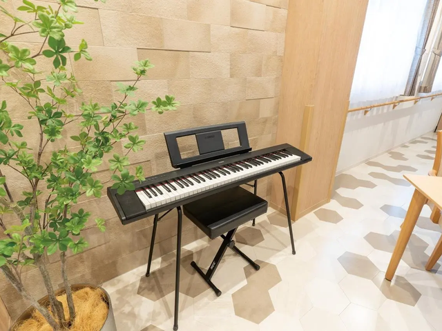 広い空間の音楽室 多目的室 自然光が入る明るい場所で、電子ピアノが設置されています。音楽活動に適した空間です。
