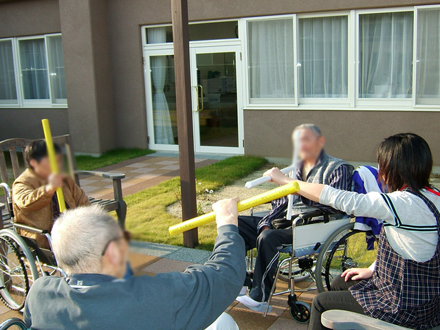 中庭で運動する人々 中庭 広々とした中庭で、車椅子の方々が楽しく運動を行っています。暖かな日差しが心地よい環境です。