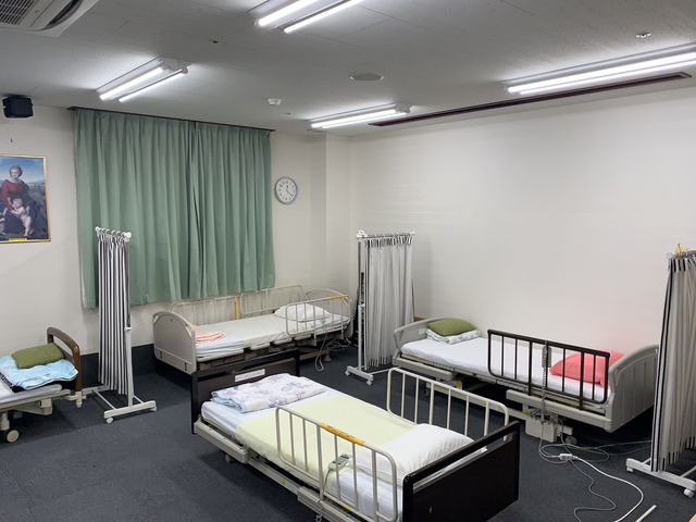 広々とした多目的室 多目的室 広々とした空間で、ベッドが複数配置されています。明るい照明が快適な雰囲気を作り出しています。