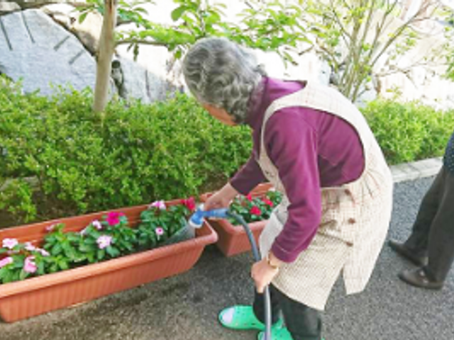 プランターで花に水やり中の庭 庭 草花が並ぶ庭では、入居者の方がリラックスしながらガーデニングを楽しめます。