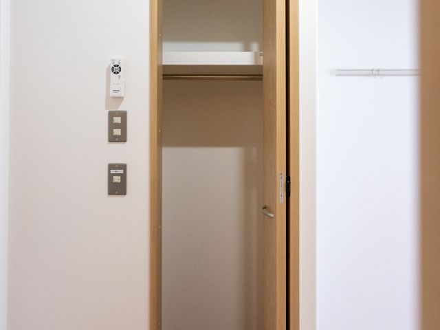 収納の扉が開いている居室 居室 壁際にクローゼットが設置されており、使いやすい収納スペースがあります。明るい木目調の床が特徴です。