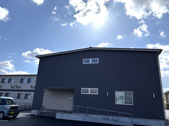 青空の下の建物外観 外観 広々とした造りの建物です。明るい日差しが差し込み、道も整備されています。