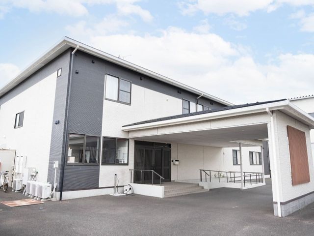 建物の外観 外観 広々とした入口とスロープがあり、どなたでも安心してご利用いただけます。青空の下に佇むモダンな建物です。